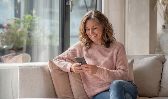 Vrouw in roze trui kijkt op haar telefoon