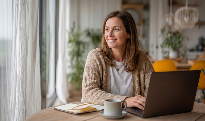 Achter een laptop zittende vrouw kijkt naar buiten